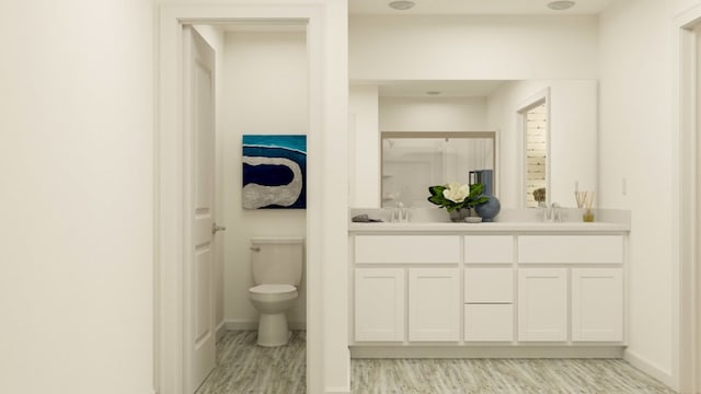 bathroom with toilet, wood-type flooring, and double vanity