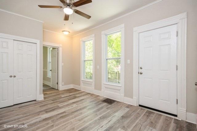 doorway with ceiling fan, ornamental molding, and light hardwood / wood-style flooring