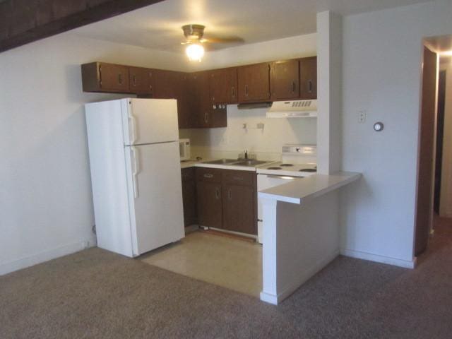 kitchen featuring sink, dark brown cabinetry, kitchen peninsula, light carpet, and white appliances