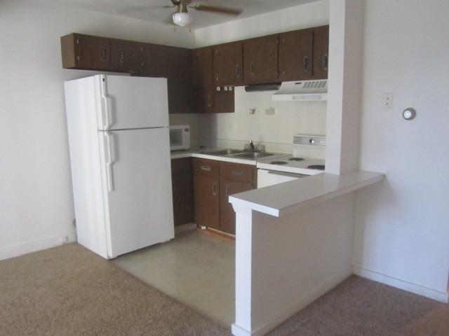 kitchen featuring ceiling fan, white appliances, sink, dark brown cabinetry, and kitchen peninsula