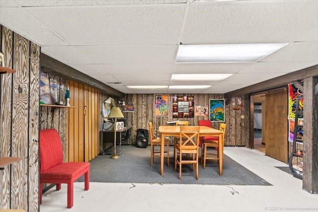 dining room featuring wood walls and a drop ceiling