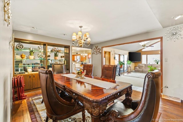 dining area with ceiling fan with notable chandelier and hardwood / wood-style floors