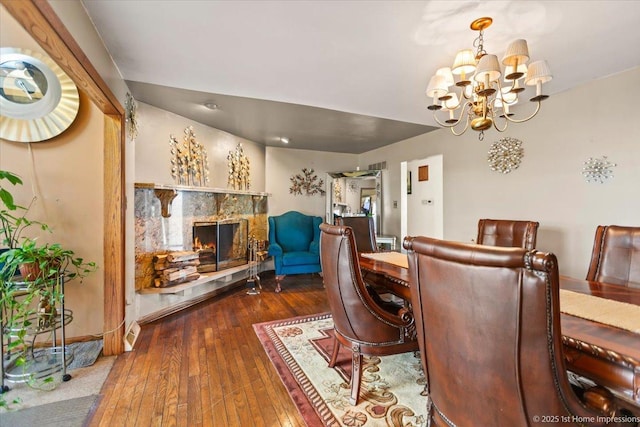 dining space with a premium fireplace, a chandelier, and dark wood-type flooring