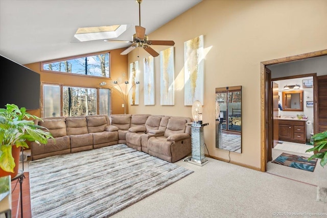 carpeted living room featuring a skylight, high vaulted ceiling, and ceiling fan