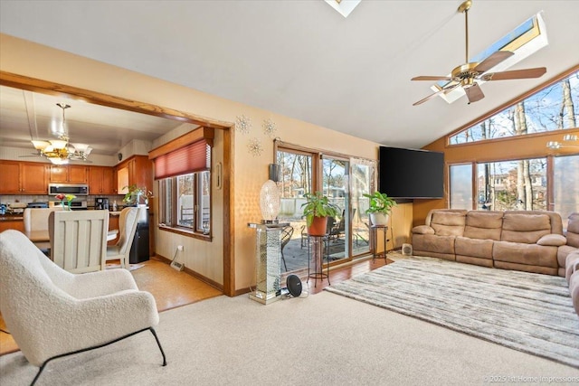 carpeted living room with ceiling fan with notable chandelier and a wealth of natural light