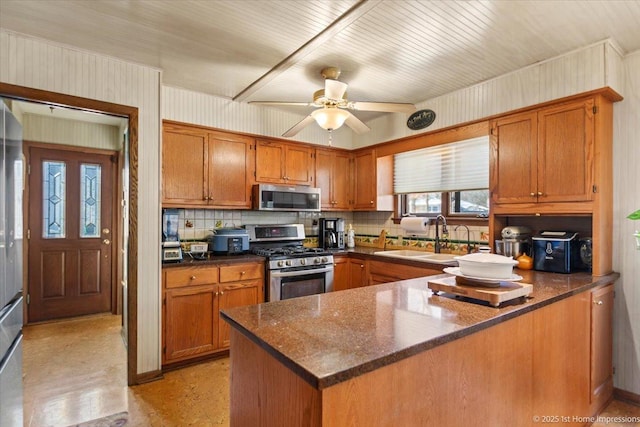 kitchen featuring stainless steel appliances, kitchen peninsula, ceiling fan, sink, and tasteful backsplash