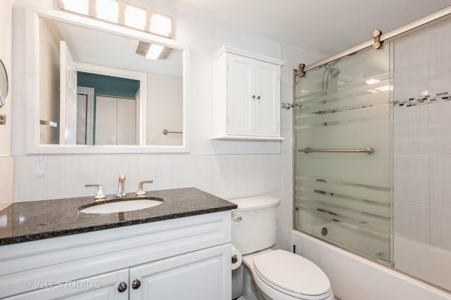 bathroom featuring toilet, combined bath / shower with glass door, and vanity