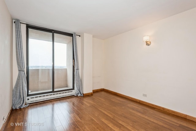 spare room with a baseboard heating unit, floor to ceiling windows, wood finished floors, and baseboards