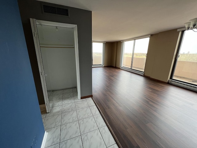 empty room with light wood-style floors, plenty of natural light, expansive windows, and visible vents