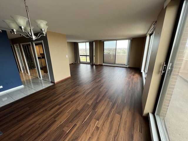 spare room with a chandelier, a baseboard radiator, dark wood finished floors, and baseboards