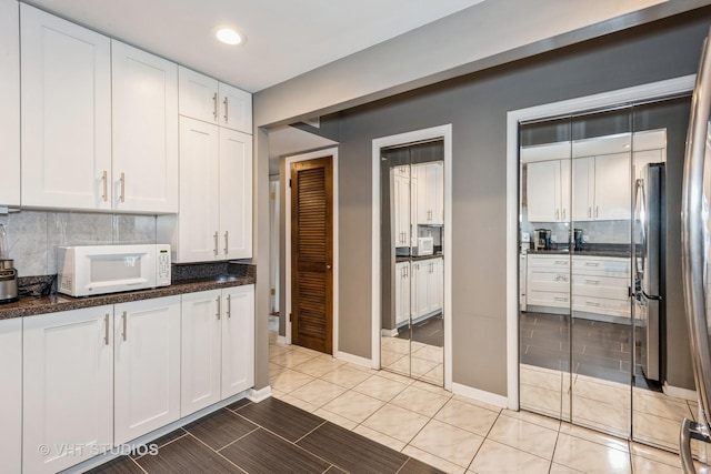 kitchen with white cabinetry, backsplash, and white microwave