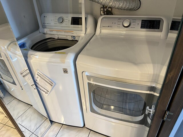 clothes washing area with laundry area, light tile patterned flooring, and washer and clothes dryer