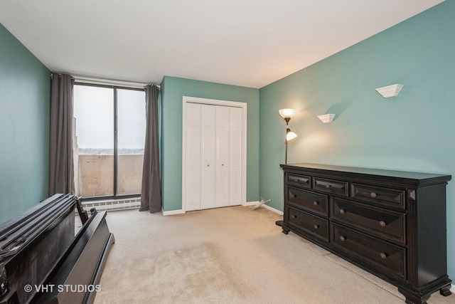 bedroom featuring light carpet, a closet, a baseboard radiator, and baseboards