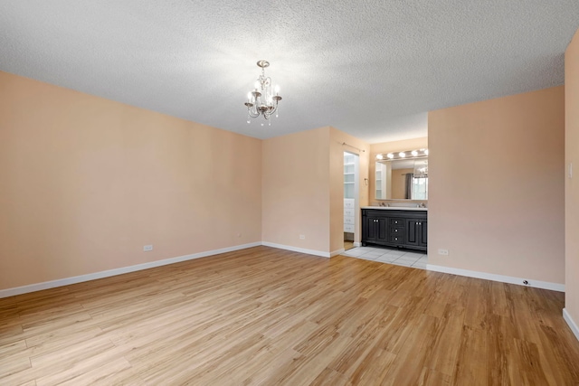 unfurnished living room featuring a chandelier, light hardwood / wood-style flooring, and a textured ceiling