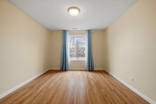 spare room featuring a textured ceiling and light hardwood / wood-style floors