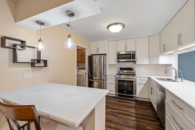 kitchen featuring sink, hanging light fixtures, stainless steel appliances, white cabinets, and washer / clothes dryer