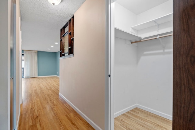 hall with a textured ceiling and light wood-type flooring