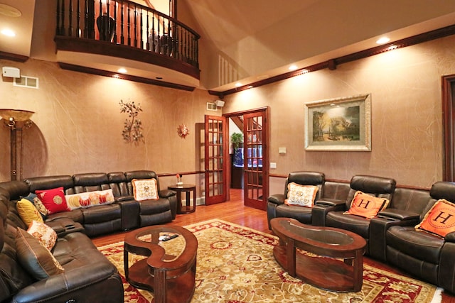 home theater featuring light hardwood / wood-style flooring, a high ceiling, and french doors