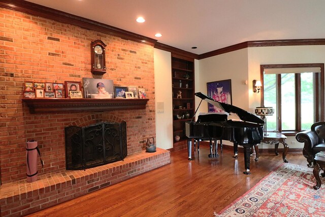 living area with hardwood / wood-style floors, a brick fireplace, and crown molding