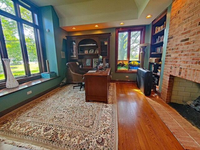 office area with hardwood / wood-style floors, plenty of natural light, and a fireplace