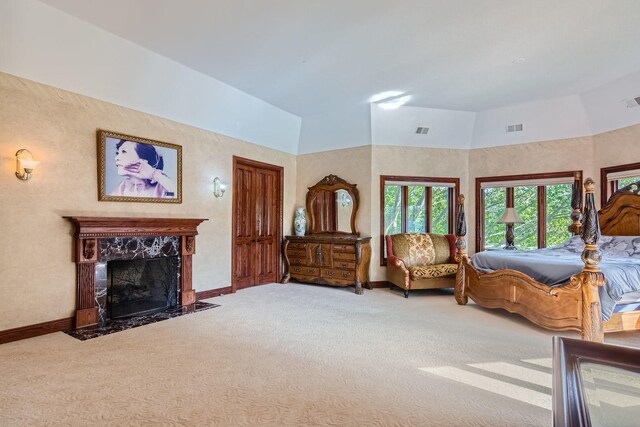 carpeted bedroom featuring a high end fireplace and vaulted ceiling