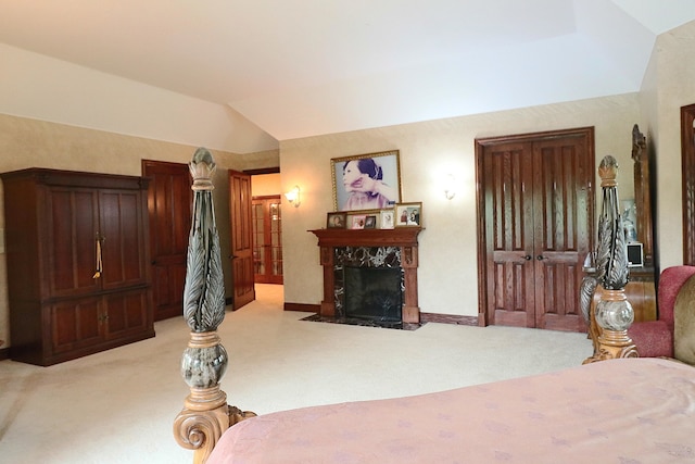 bedroom with a fireplace, light colored carpet, and lofted ceiling