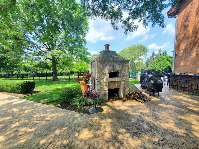 exterior space with an outdoor stone fireplace, a bar, and grilling area