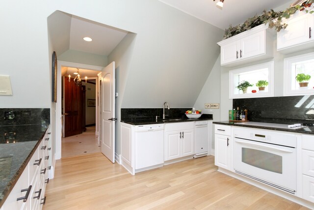 kitchen featuring white appliances, a notable chandelier, dark stone countertops, white cabinets, and light hardwood / wood-style floors