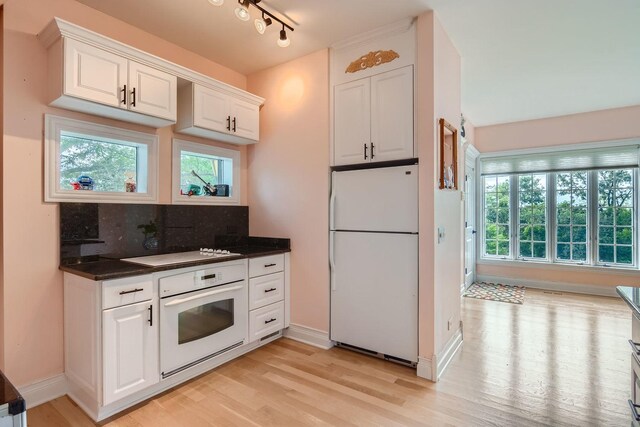 kitchen with white appliances, tasteful backsplash, white cabinetry, and plenty of natural light