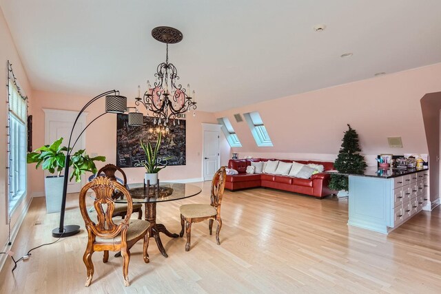 dining room with a skylight, light hardwood / wood-style flooring, and a chandelier