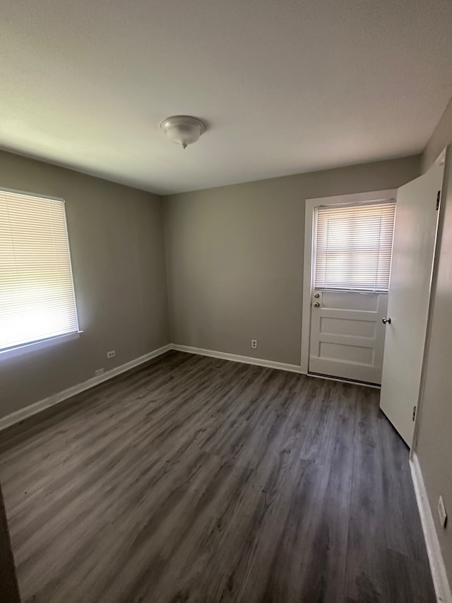 empty room with dark hardwood / wood-style flooring and a wealth of natural light