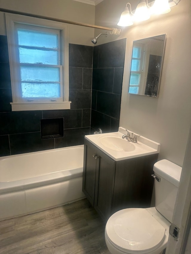 full bathroom with tiled shower / bath, toilet, vanity, wood-type flooring, and ornamental molding