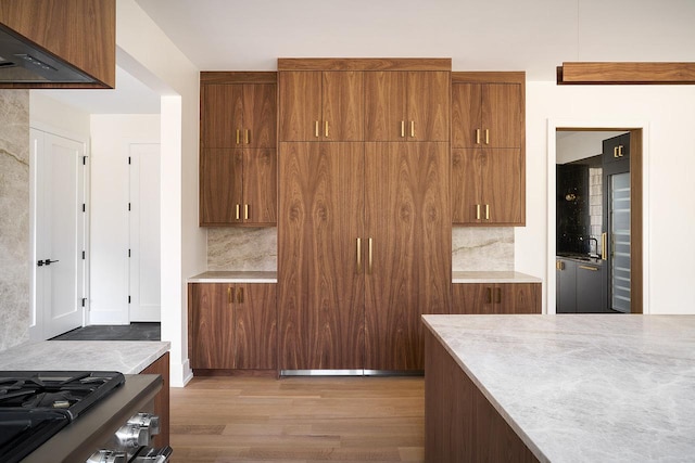 kitchen with tasteful backsplash, stainless steel gas range, and light hardwood / wood-style flooring