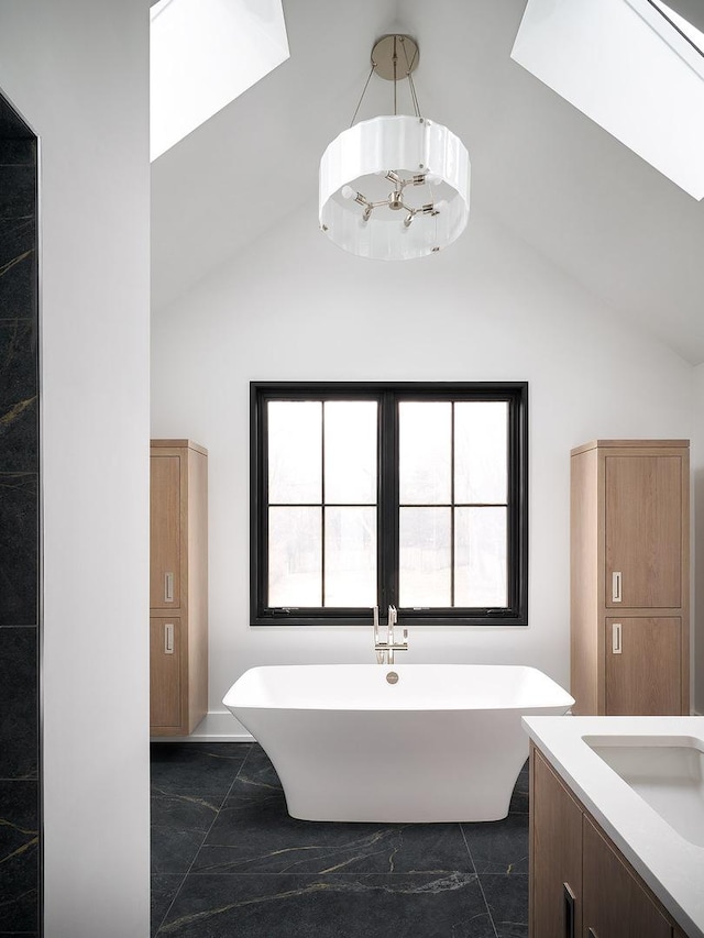 bathroom with vaulted ceiling, a bathing tub, and vanity