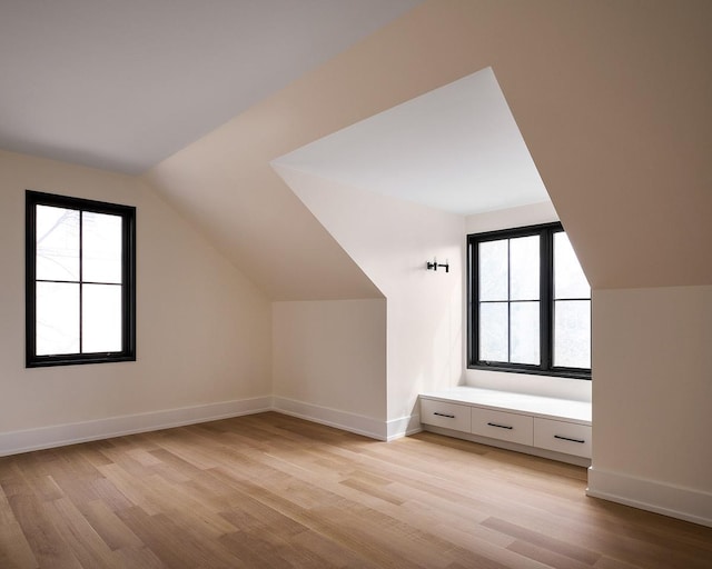 additional living space featuring lofted ceiling and light hardwood / wood-style flooring