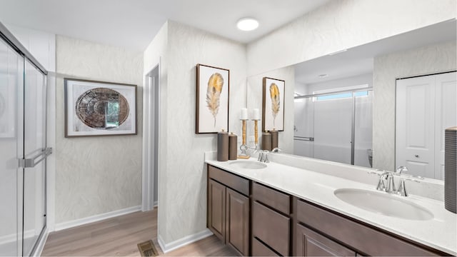 bathroom featuring a shower with shower door, double sink vanity, and hardwood / wood-style floors