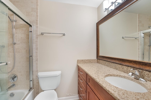 bathroom featuring toilet, combined bath / shower with glass door, and vanity