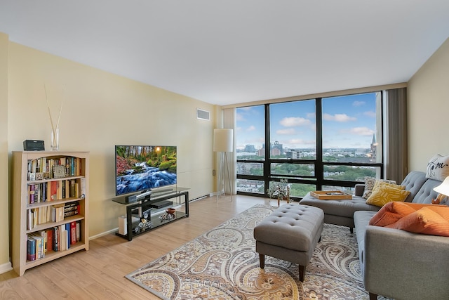 living room with light wood-style floors, baseboards, expansive windows, and visible vents