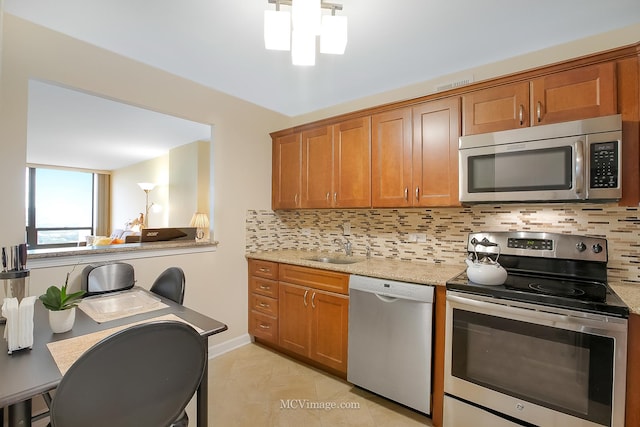 kitchen featuring appliances with stainless steel finishes, brown cabinets, a sink, and tasteful backsplash