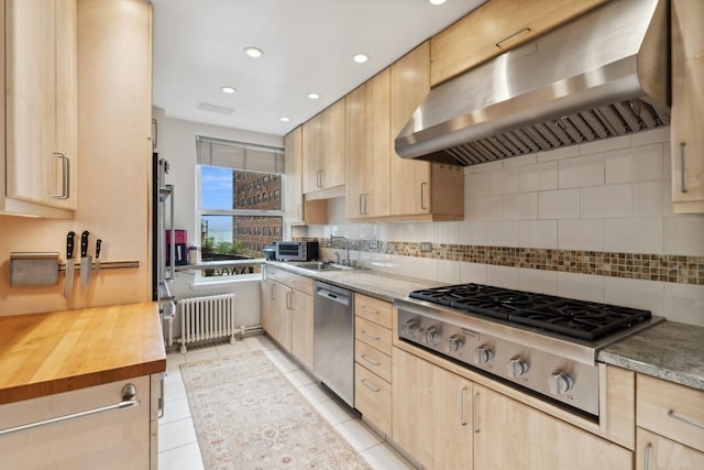 kitchen featuring tasteful backsplash, exhaust hood, light tile patterned flooring, radiator, and stainless steel appliances