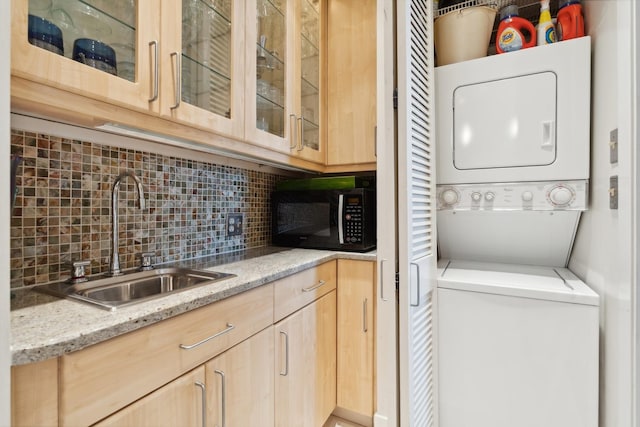 laundry room featuring stacked washer and dryer and sink