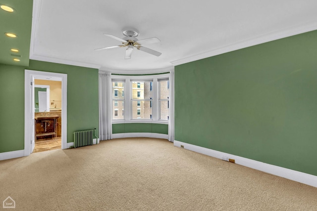 empty room with radiator, ceiling fan, carpet, and crown molding