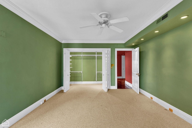 unfurnished bedroom featuring ceiling fan, a closet, crown molding, and carpet floors