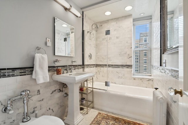 bathroom with bath / shower combo with glass door and tile walls