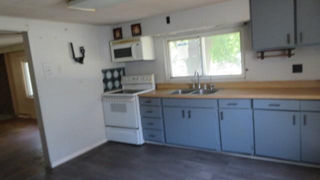 kitchen with sink, dark hardwood / wood-style floors, white appliances, and blue cabinetry