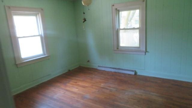 spare room with a baseboard heating unit and dark hardwood / wood-style flooring