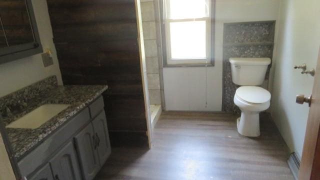 bathroom featuring toilet, a shower, hardwood / wood-style floors, and vanity