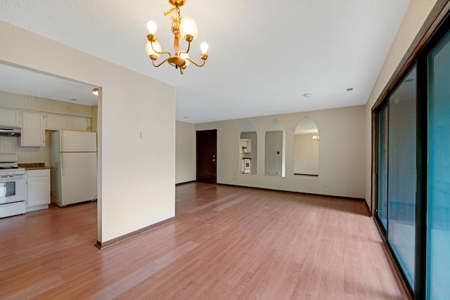 unfurnished living room with light hardwood / wood-style floors and a notable chandelier