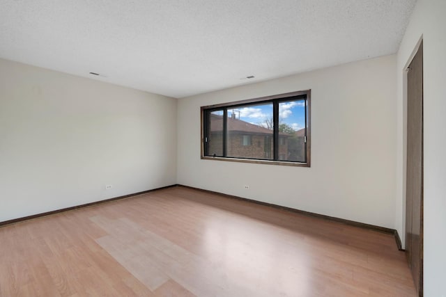 spare room featuring light hardwood / wood-style floors and a textured ceiling