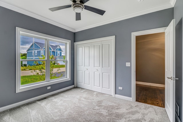 unfurnished bedroom featuring multiple windows, light carpet, ceiling fan, and ornamental molding